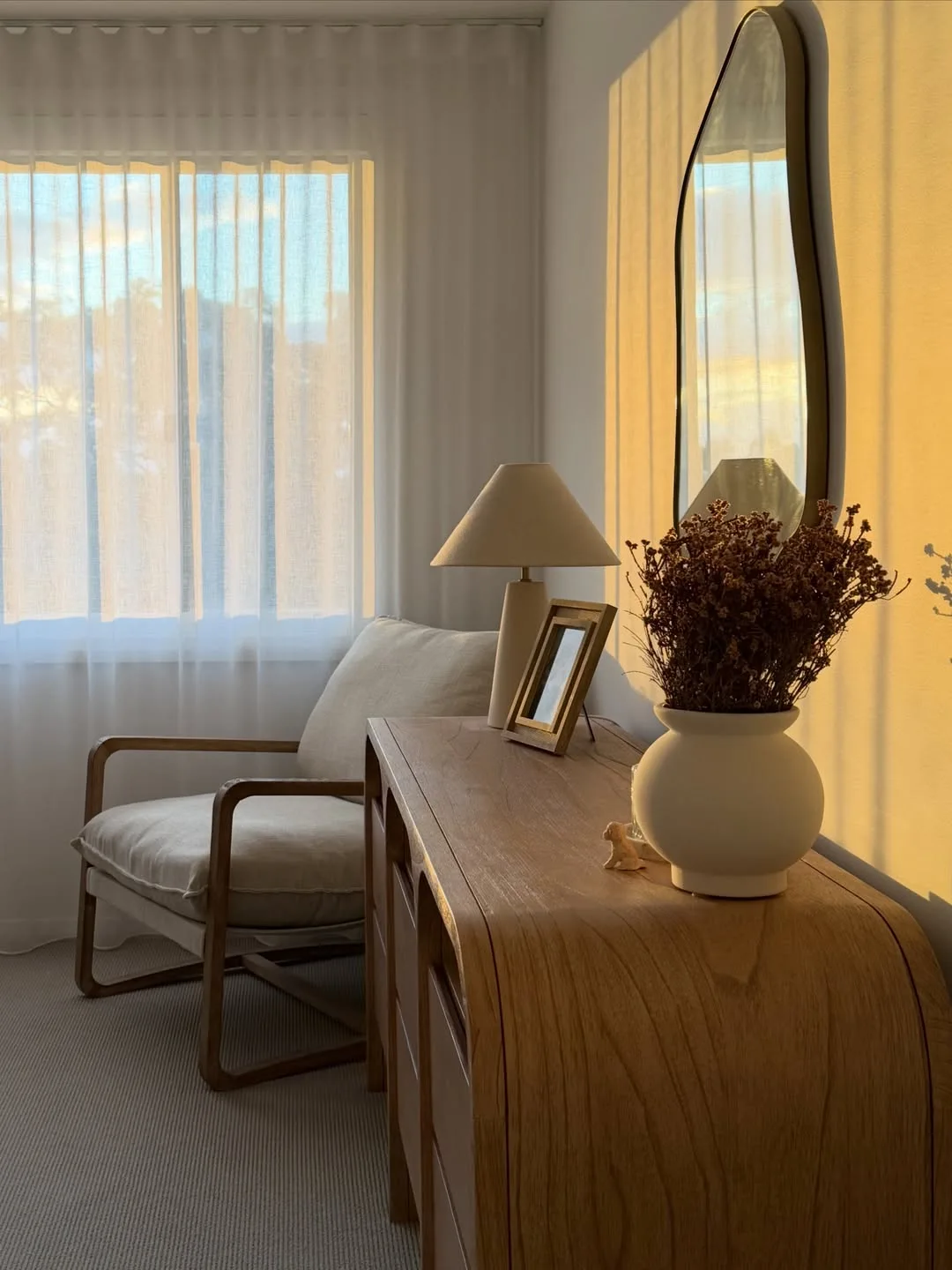 Golden light over our timber bedroom dresser and sheer curtains