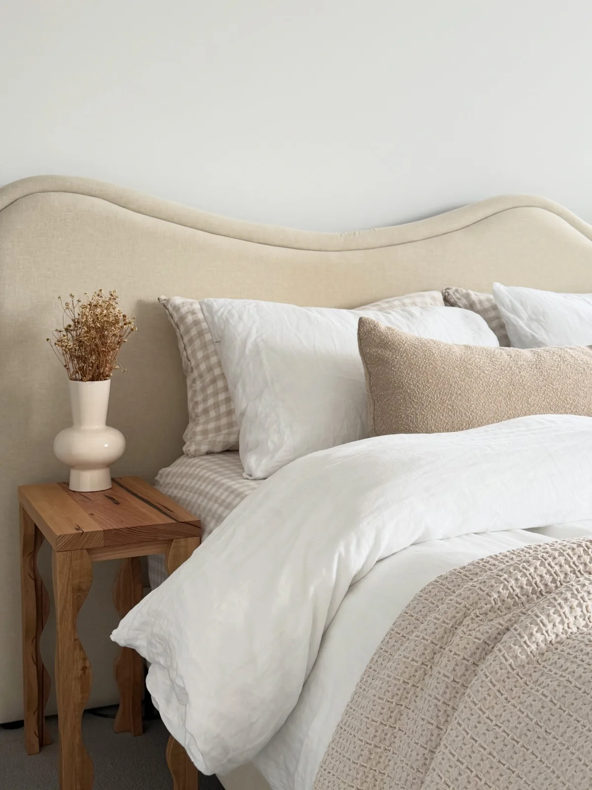 Rustic timber stool beside our cream upholstered bed