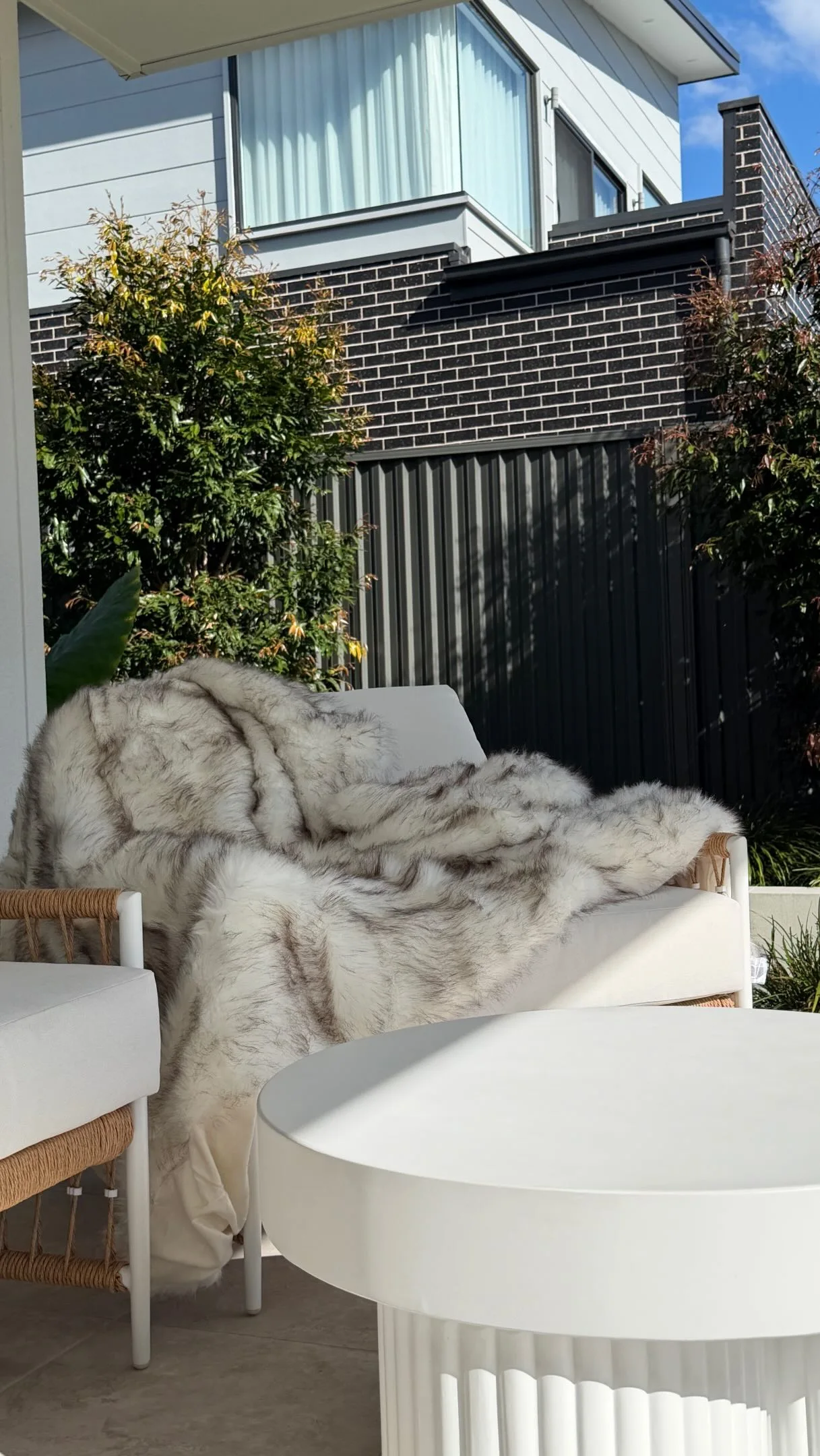 Soft faux-fur throw draped over our outdoor sofa in the sunshine