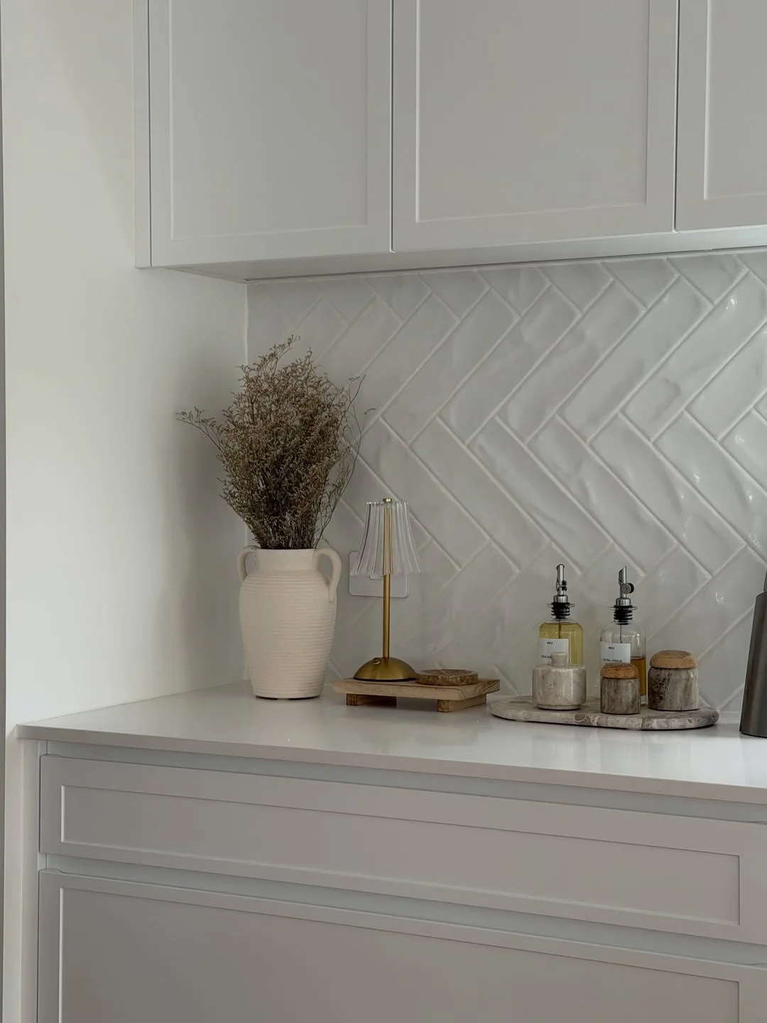 White herringbone splashback and neutral kitchen styling