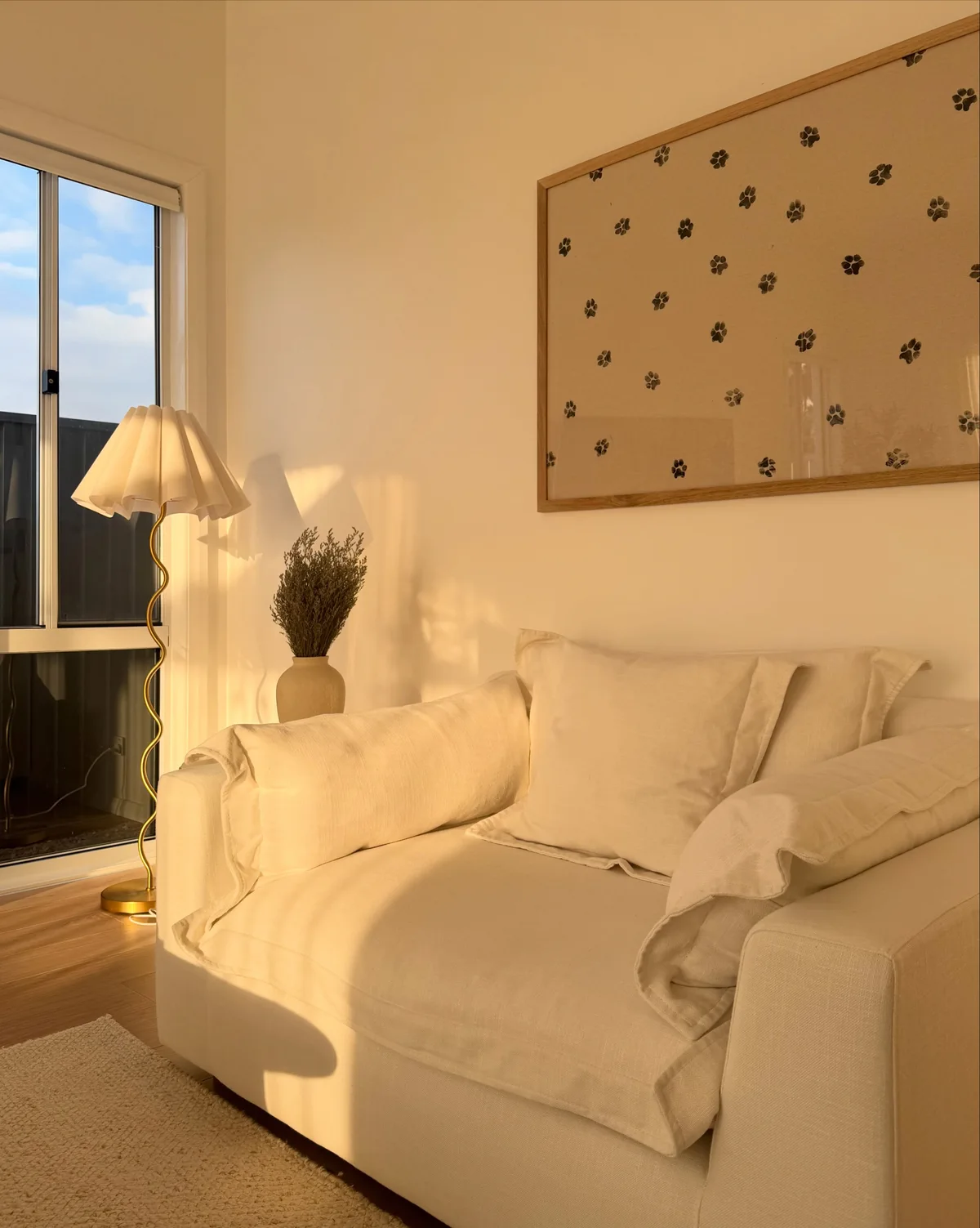 White wall sconce beside the floor lamp behind our cream living-room sofa